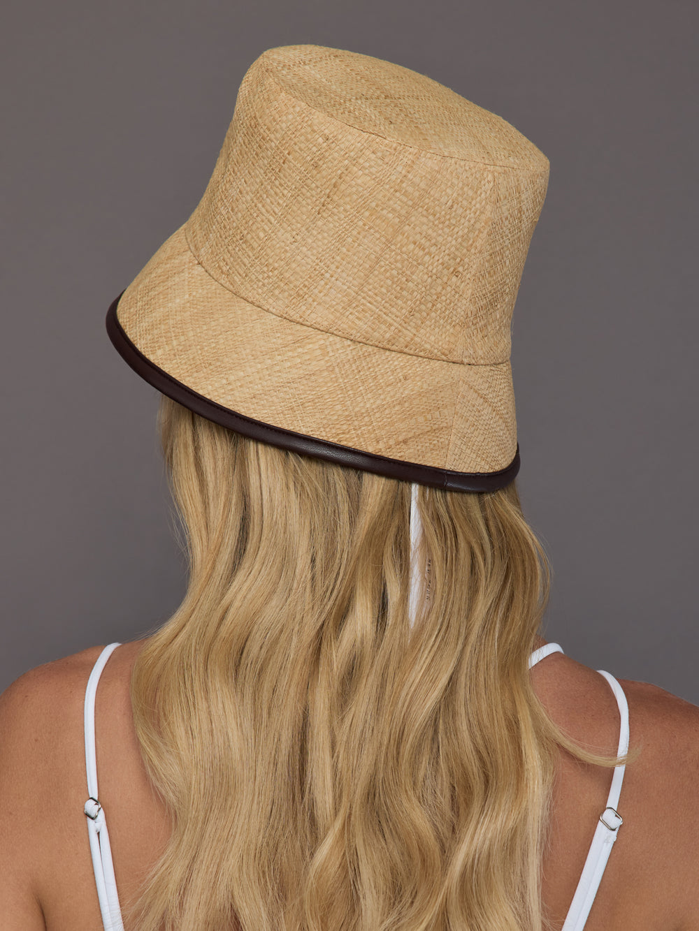 Back view of natural woven straw bucket hat showing contrast trim edge.