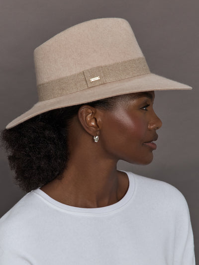 Model wearing a beige hat against a gray background