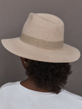 Model wearing a beige hat against a gray background