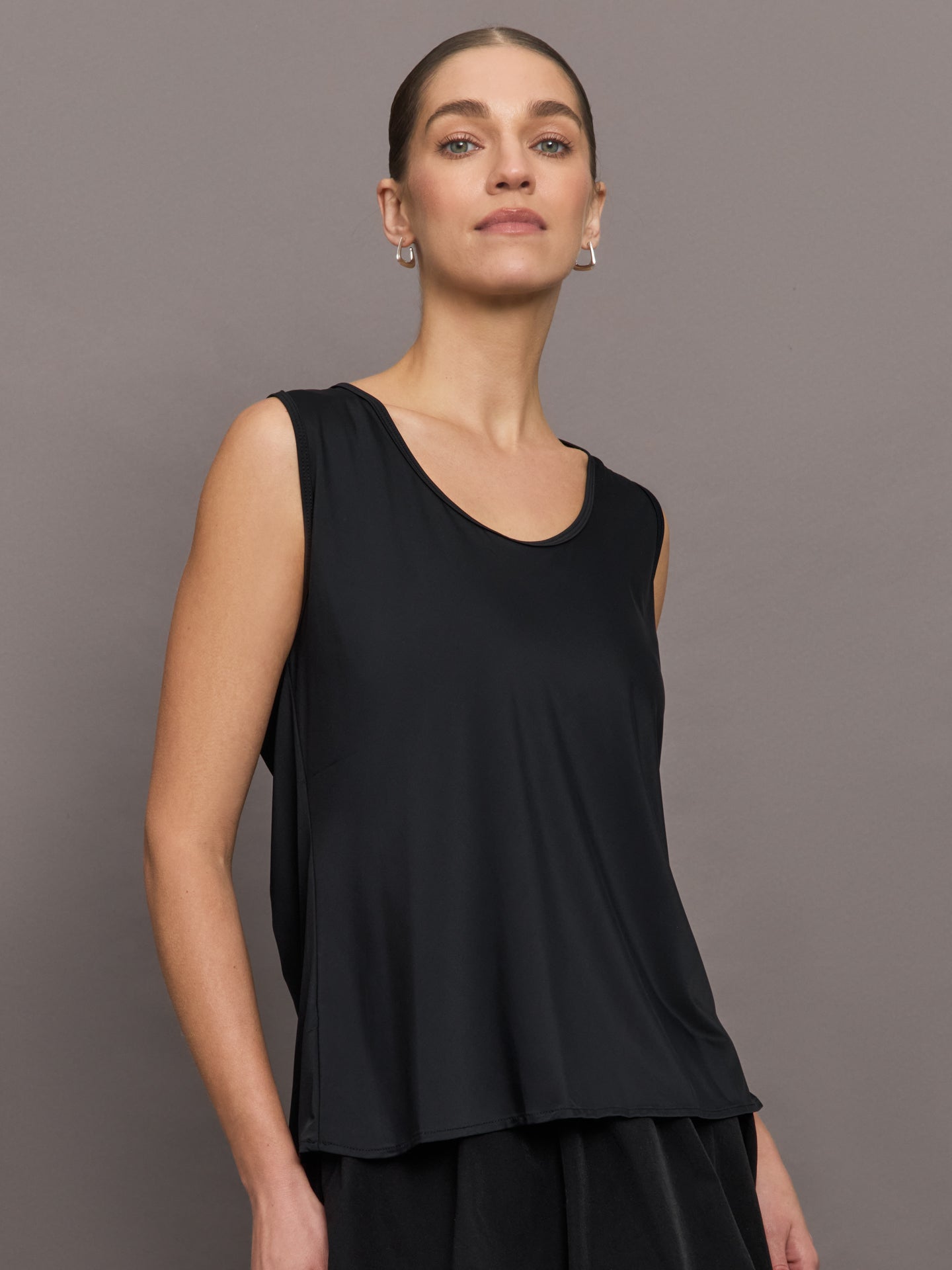 Model wears a loosely fitted round neck black tank top. 