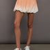 Model is wearing a peach ombre skirt perfect for tennis with built in shorts.