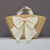 Front view of oversized straw tote with large ivory satin bow.