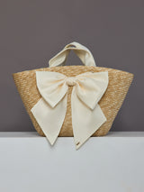 Front view of oversized straw tote with large ivory satin bow.