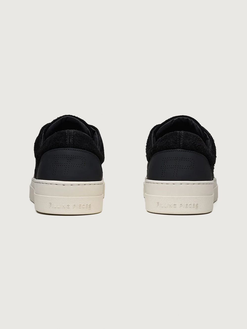 Filling Pieces Riviera Fuzz sneakers in black with suede heel panel, perforated FP logo, and white rubber sole, back view.