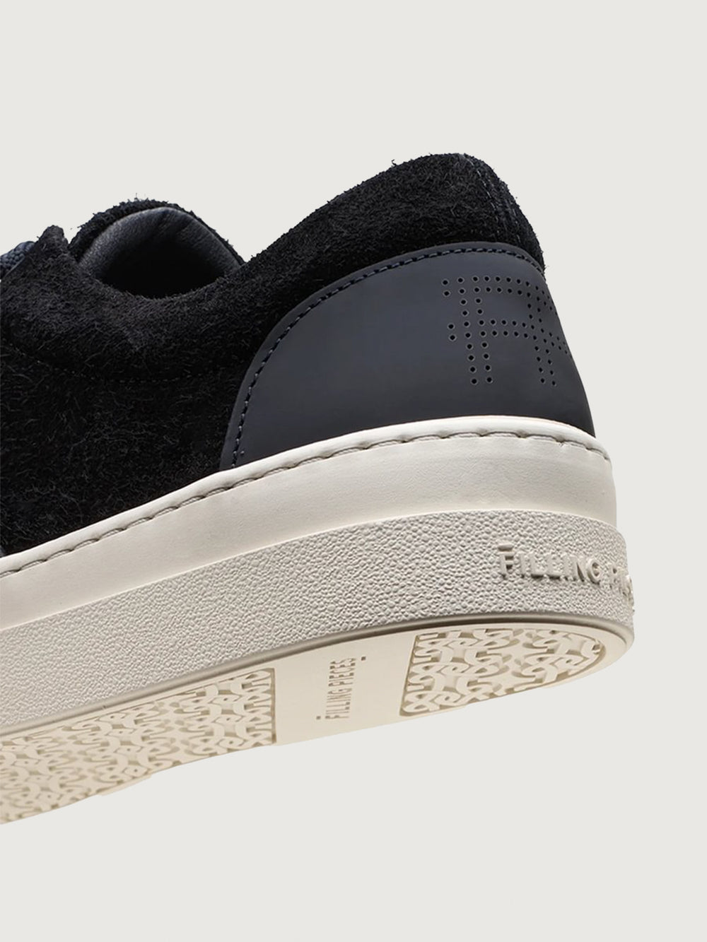 Close-up of Filling Pieces Riviera Fuzz sneaker in black with embossed FP heel tab, white sole branding, and textured outsole.