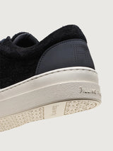 Close-up of Filling Pieces Riviera Fuzz sneaker in black with embossed FP heel tab, white sole branding, and textured outsole.