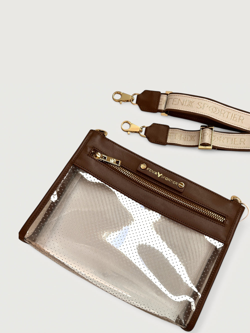 Clear vinyl pouch with perforated finish, brown leather trim, gold zipper, and detachable logo strap.