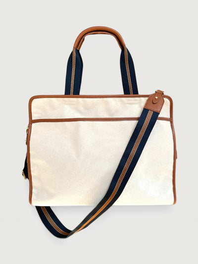 Canvas and leather tote bag in cream with tan trim, front view with detachable striped shoulder strap.