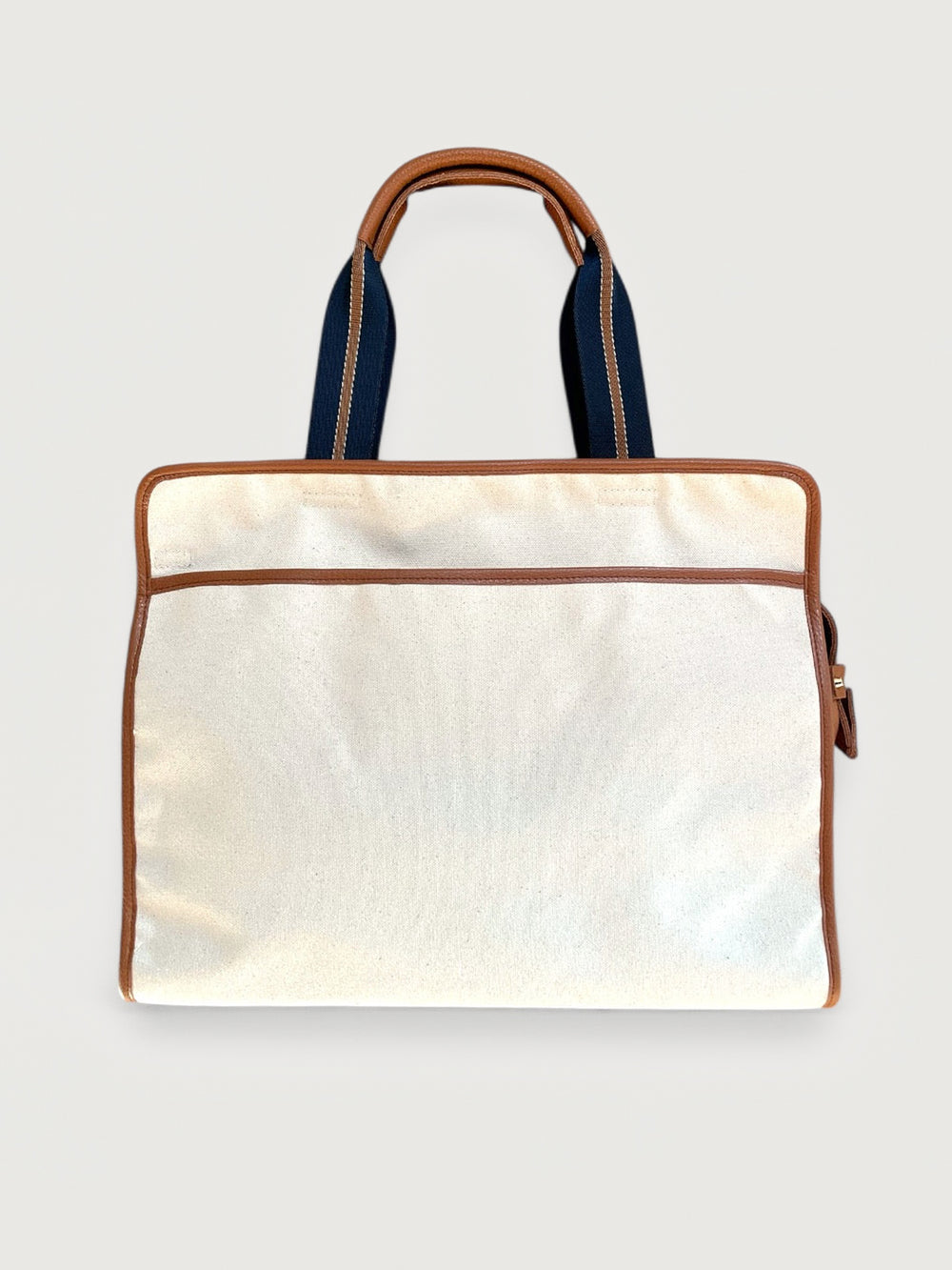 Canvas tote bag in cream with tan leather trim, back pocket detail.