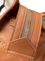 Close-up of tan leather zipper detail with gold hardware on canvas tote bag.