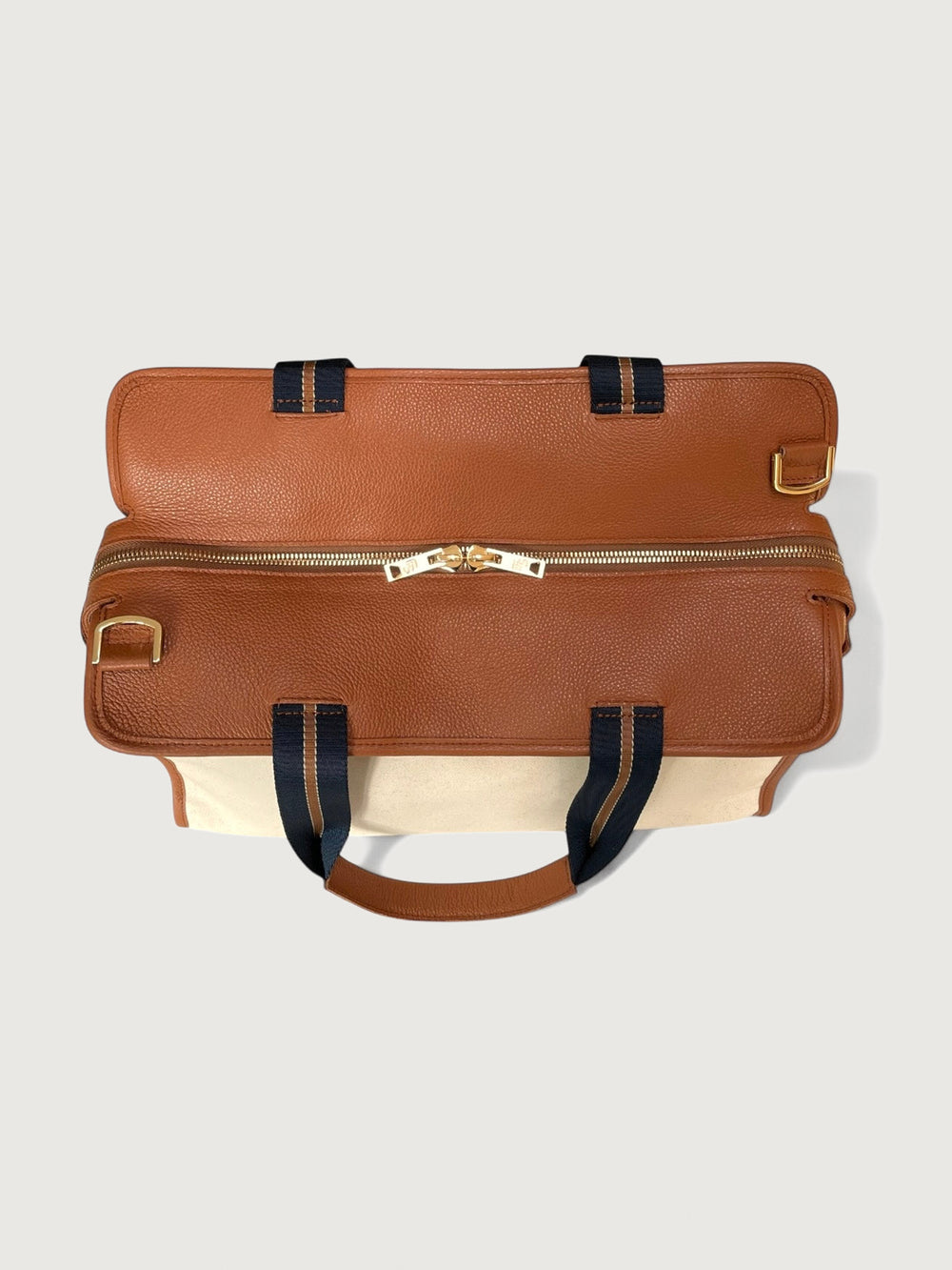 Top view of cream canvas tote bag with tan leather trim and gold zipper closure.