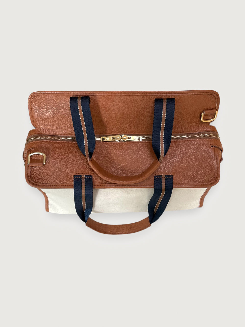 Open top view of tote bag in cream canvas and tan leather with navy striped handles.