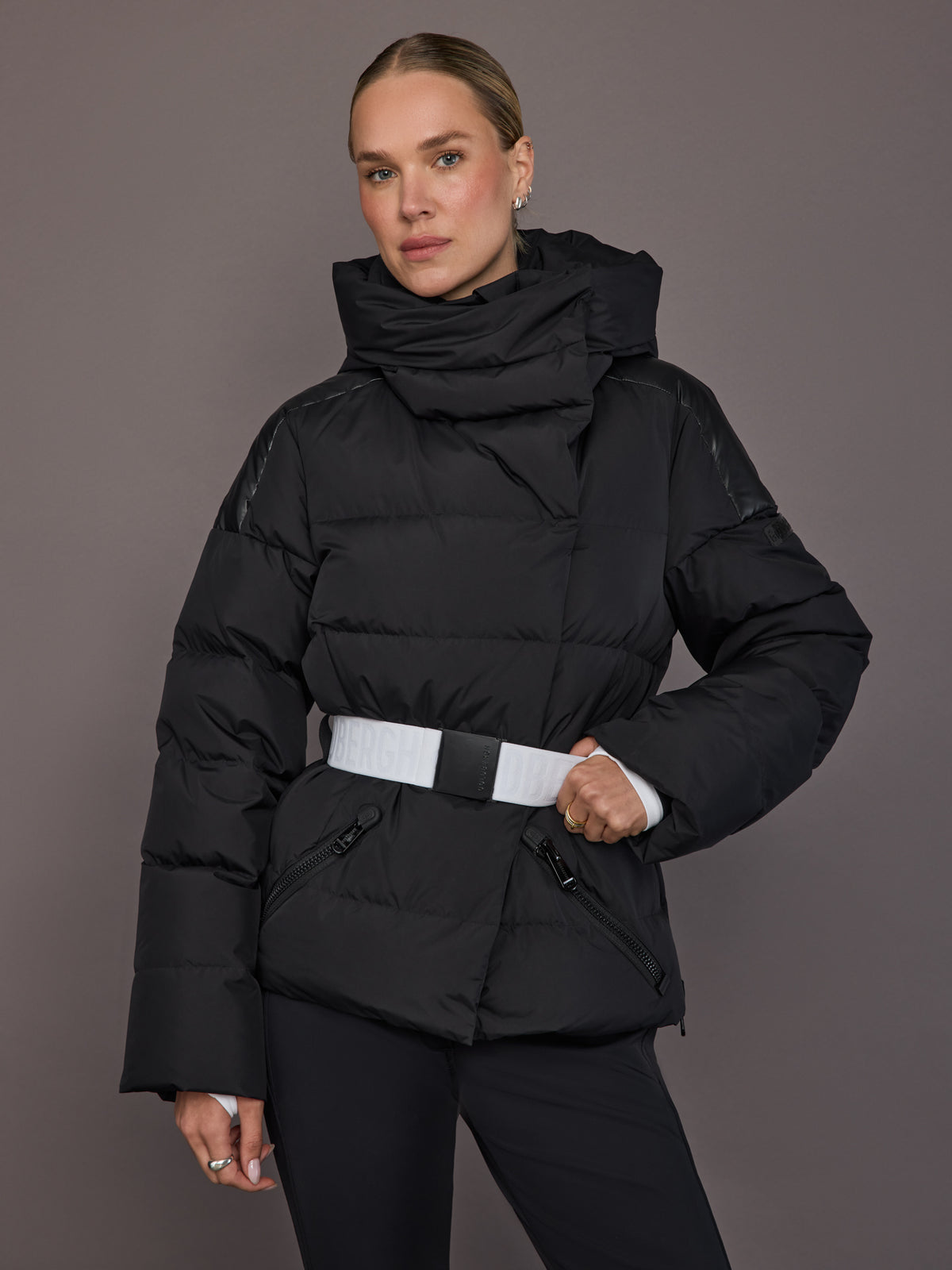 Model wearing the Bufera Ski Jacket in black, front view with belted waist and high collar.