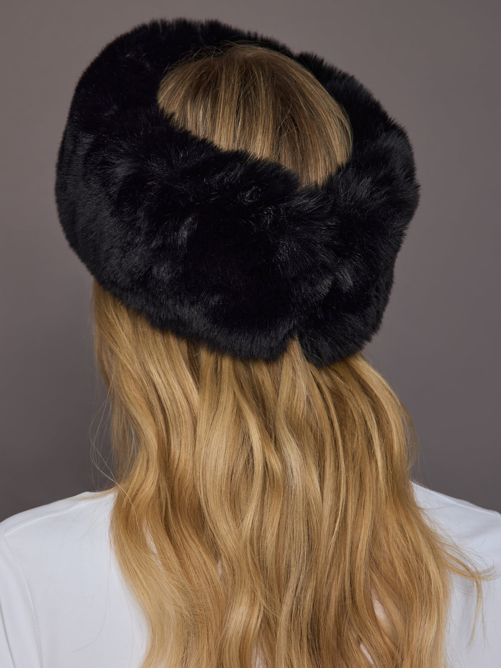 Black faux fur headband on model, back view showing elastic detail.