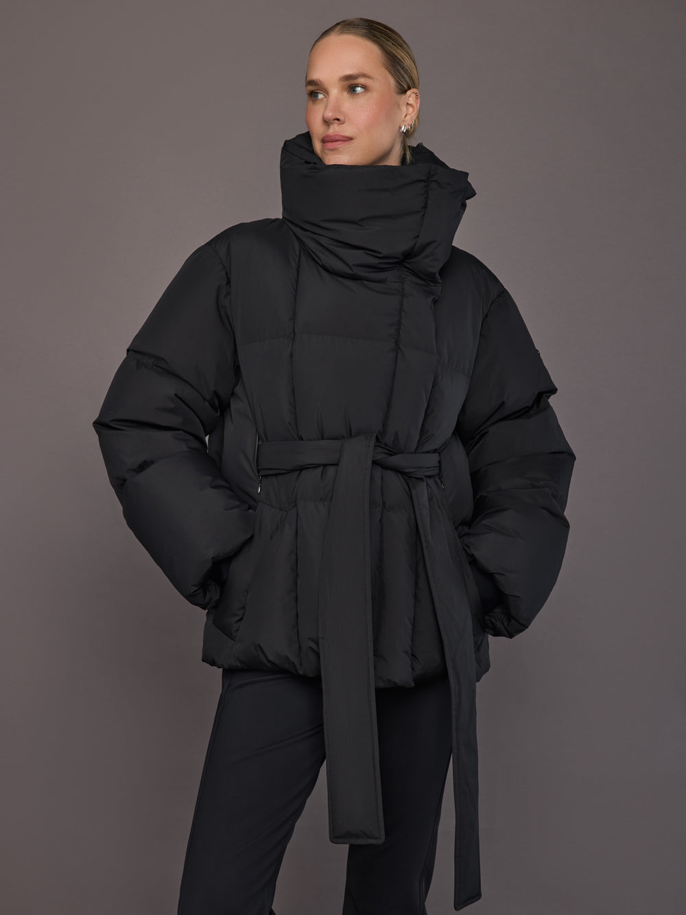 Black quilted down jacket on model, front view with tall collar.