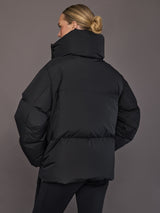 Black quilted down jacket on model, back view with tall collar.