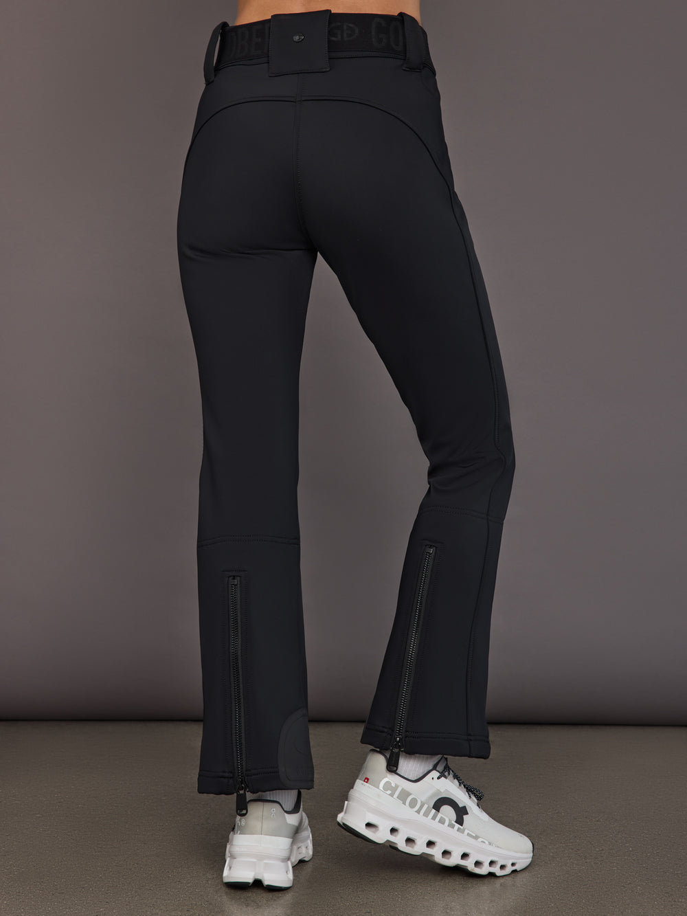 Black softshell ski pant on model, back view with hem zippers.