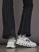 Black softshell ski pant on model, close back view of hem zippers and snowcatchers.