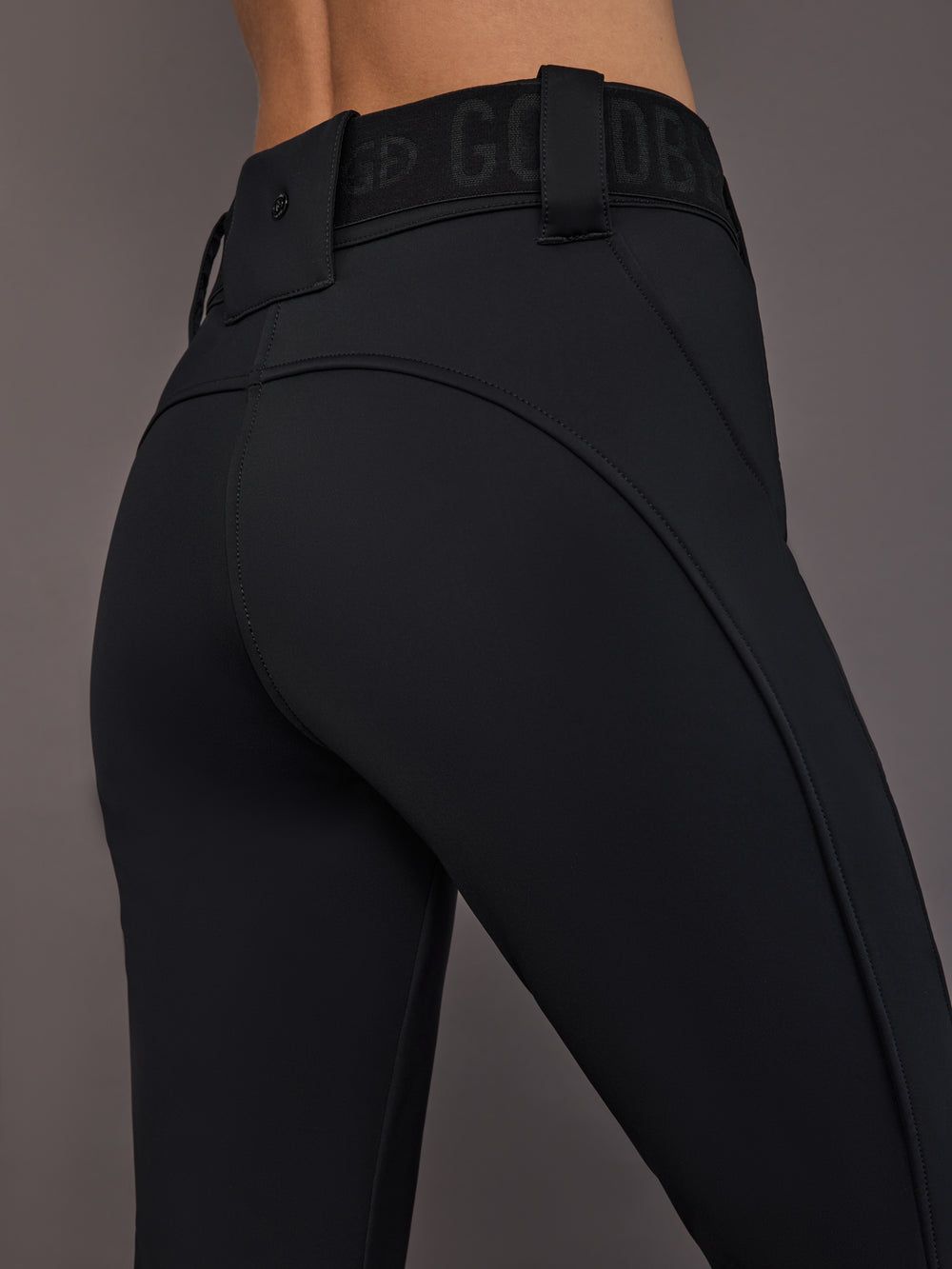 Black softshell ski pant on model, close side view of waist and seams.