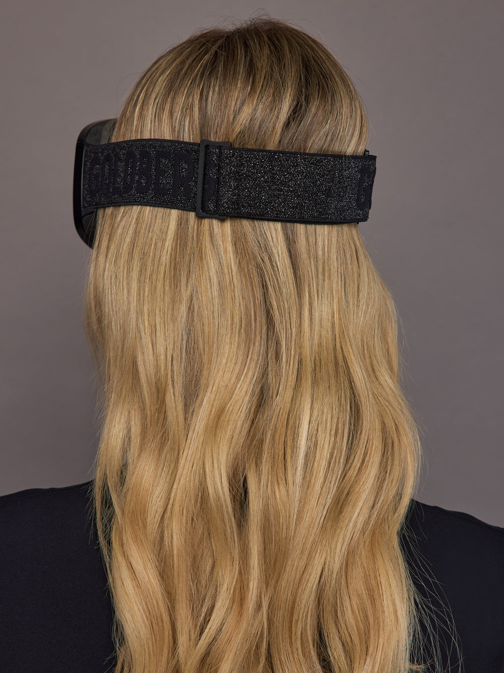 Black frameless ski goggle on model, back view with full strap detail.