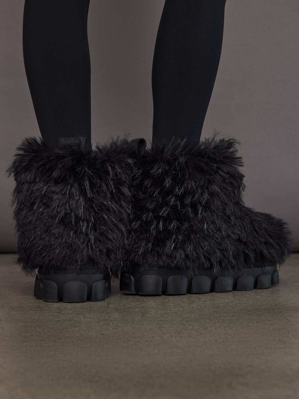 Black faux fur low snowboot on model, back view showing low shaft and faux fur texture.