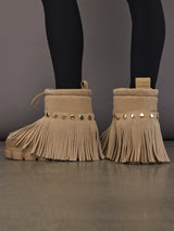 Model is wearing the Vergara Snowboot Low in Caramello, back view showing studs and fringe.