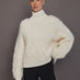 Model is wearing a cream oversized turtleneck sweater, front view showing fluffy knit texture.