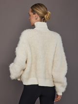 Model is wearing a cream oversized turtleneck sweater, back view showing relaxed silhouette.