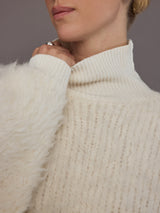 Close up of cream oversized turtleneck sweater, ribbed collar and fuzzy knit detail.