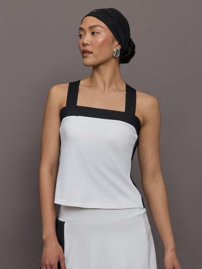 Model wears a white tank top with black straps and square neck detailing.