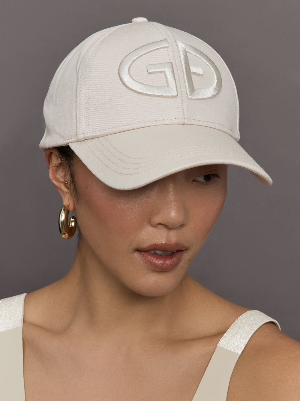 Model wears an off white baseball cap with Goldbergh logo on front.