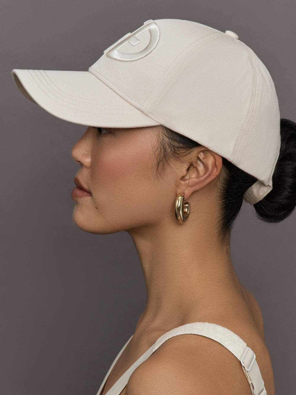Model wears an off white baseball cap with Goldbergh logo on front.