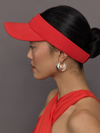 Model wears a bright red visor with Goldbergh logo on front.