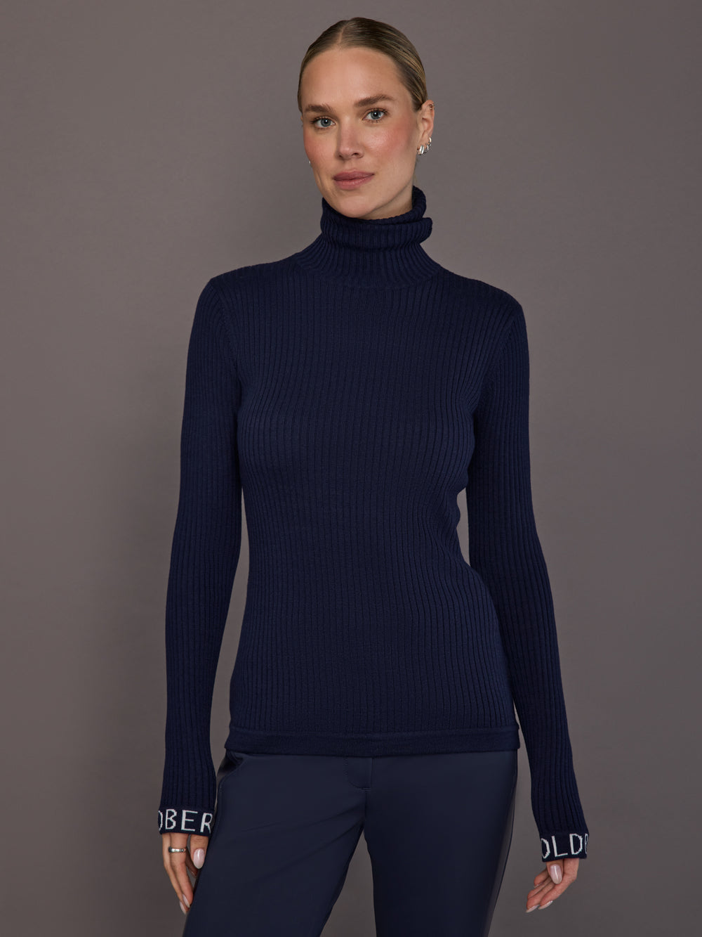Model wearing ribbed navy turtleneck sweater, front view.