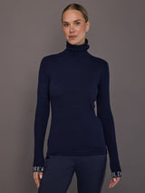 Model wearing ribbed navy turtleneck sweater, front view.