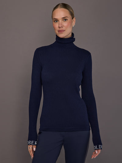 Model wearing ribbed navy turtleneck sweater, front view.