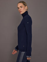 Model wearing navy ribbed turtleneck sweater, side view.