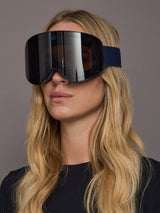 Model wearing frameless navy ski goggles, front view.
