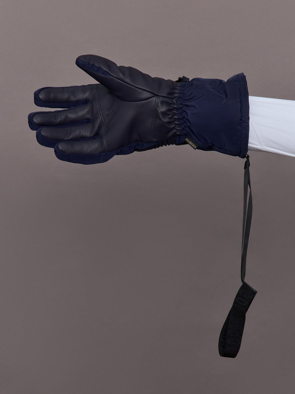 Model wearing navy quilted leather ski glove, palm view with adjustable wrist strap detail.