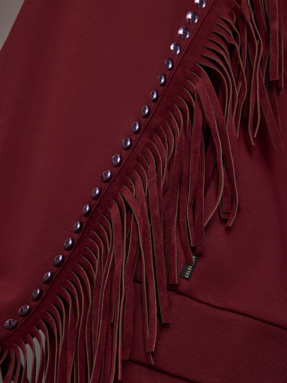 Close-up of fringe and stud detailing on Frenzy Crew Neck Fringe Sweatshirt in Vino Rosso.