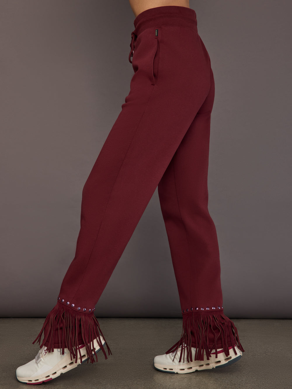 Model wearing vino rosso track pants, side view.
