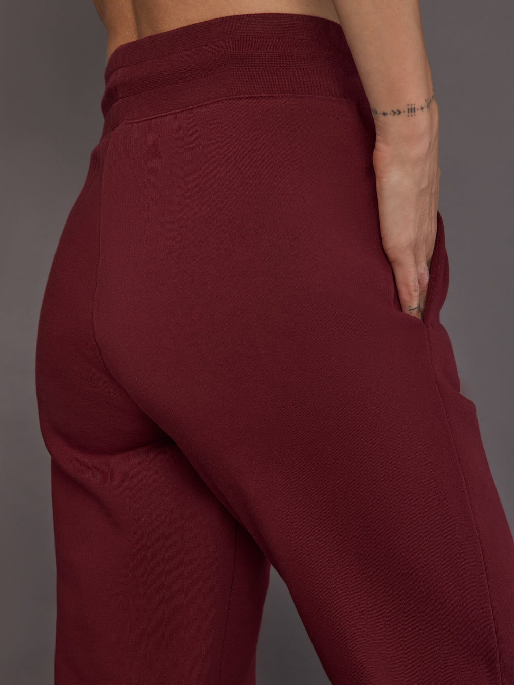Close-up of pocket detail on vino rosso track pants.
