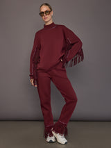 Model is wearing Frenzy Crew Neck Fringe Sweatshirt in Vino Rosso, full body view with matching pants.