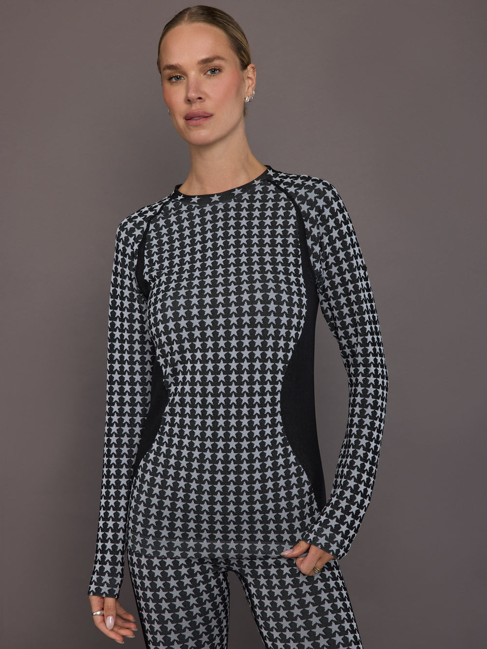 Model is wearing the Starlet Seamless Baselayer Long Sleeve in Black White Star, front view showing the all-over star knit and contour paneling.