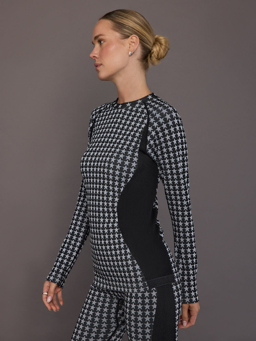 Model is wearing the Starlet Seameless Baselayer Long Sleeve in Black White Star, side profile highlighting the ribbed contour panels.