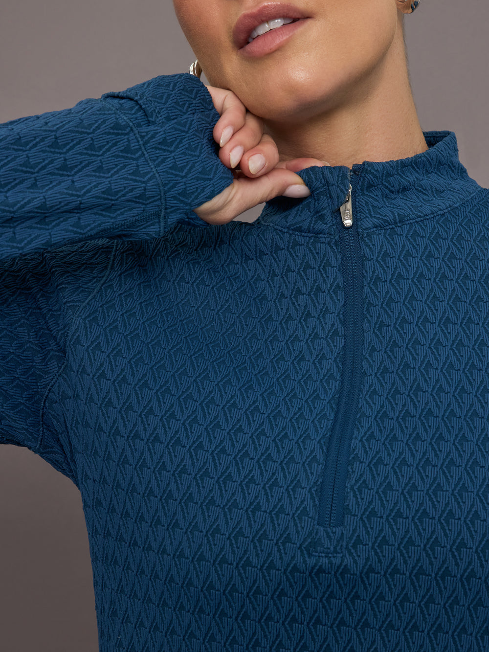 Model is wearing a blue quarter zip long sleeve fitted top 