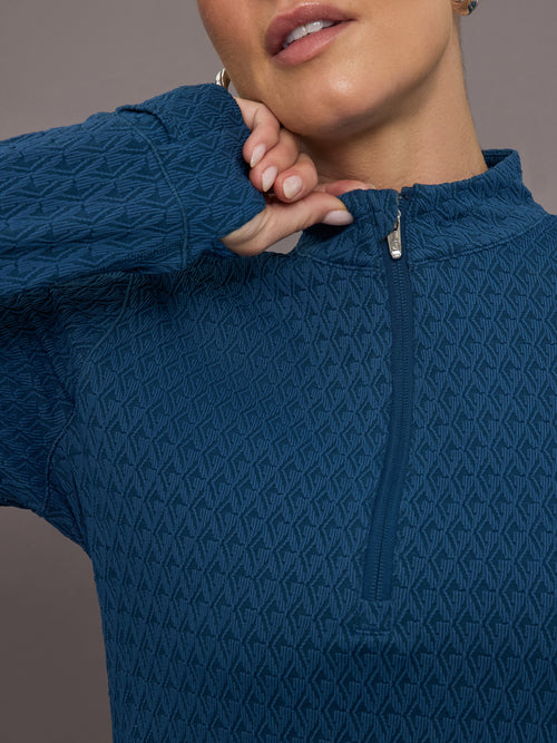 Model is wearing a blue quarter zip long sleeve fitted top 