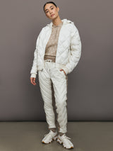 Person wearing a white puffer jacket and pants against a gray background