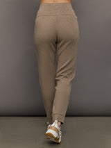 Brown sweatpants worn by a person on a gray background