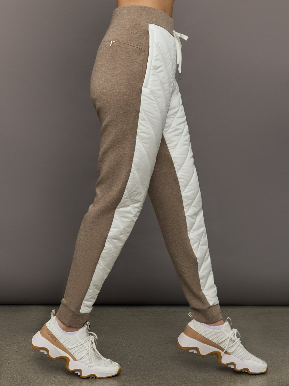 Brown and white jogger pants with a gray background